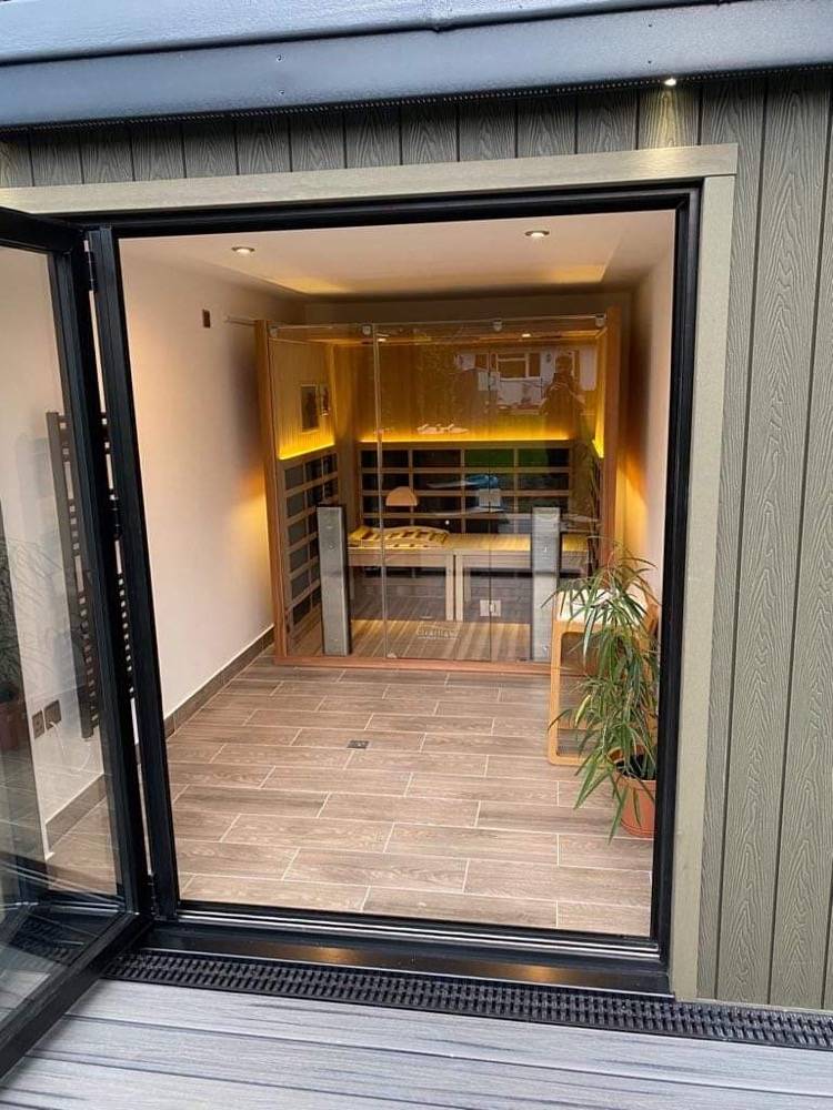 View into a bespoke garden room with timber-lined interior through bifold doors