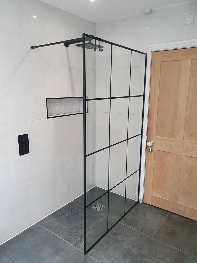 Wet room with black framed Crittall-style glass shower screen on grey tiling in Eastcote