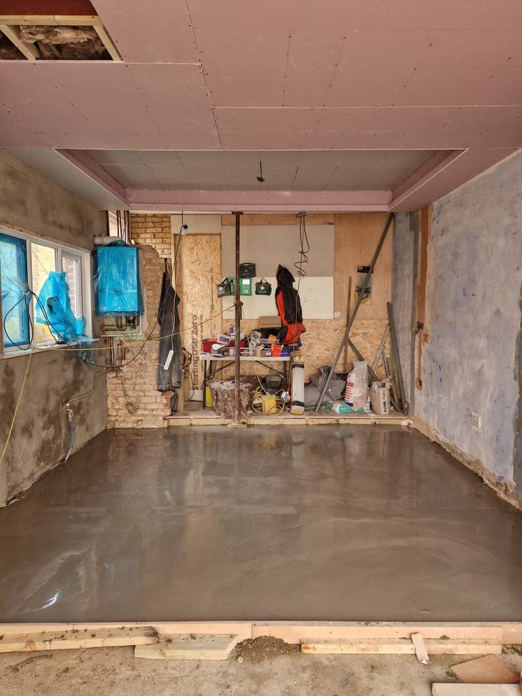 Garage conversion in progress showing new concrete floor and primed walls