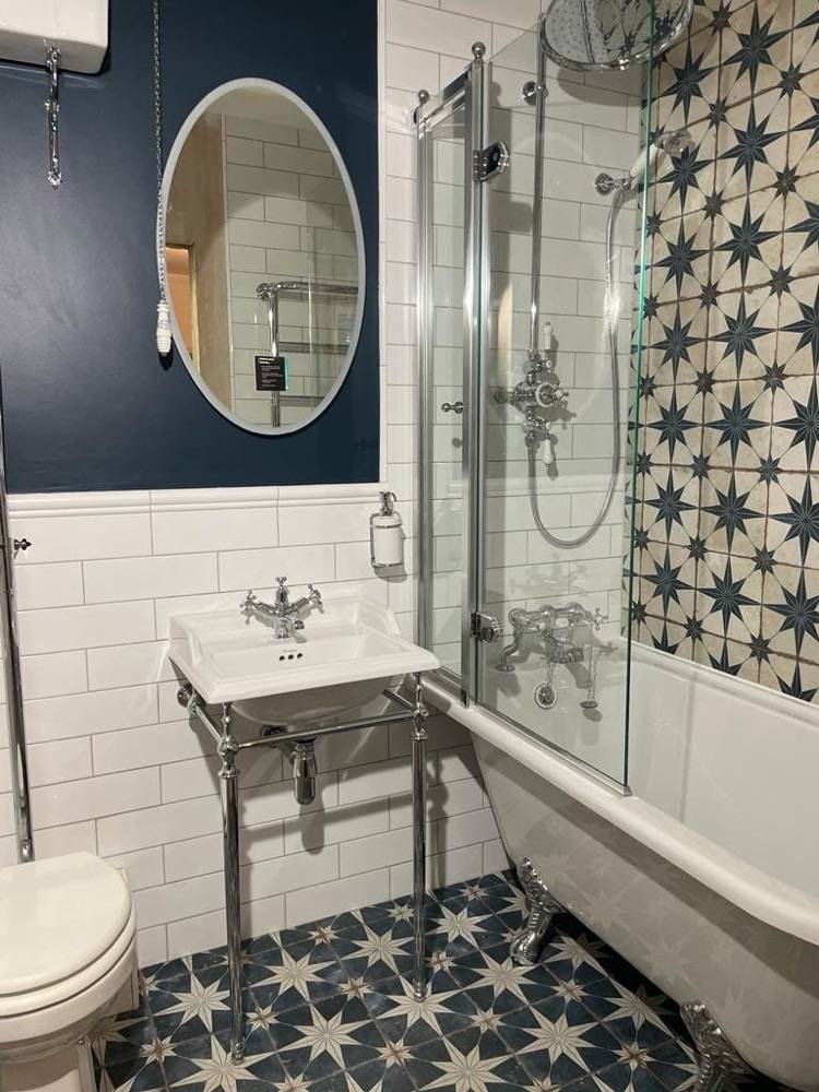 Refurbished bathroom with vanity sink, shower-over-bath and patterned starry tile by DR Construction