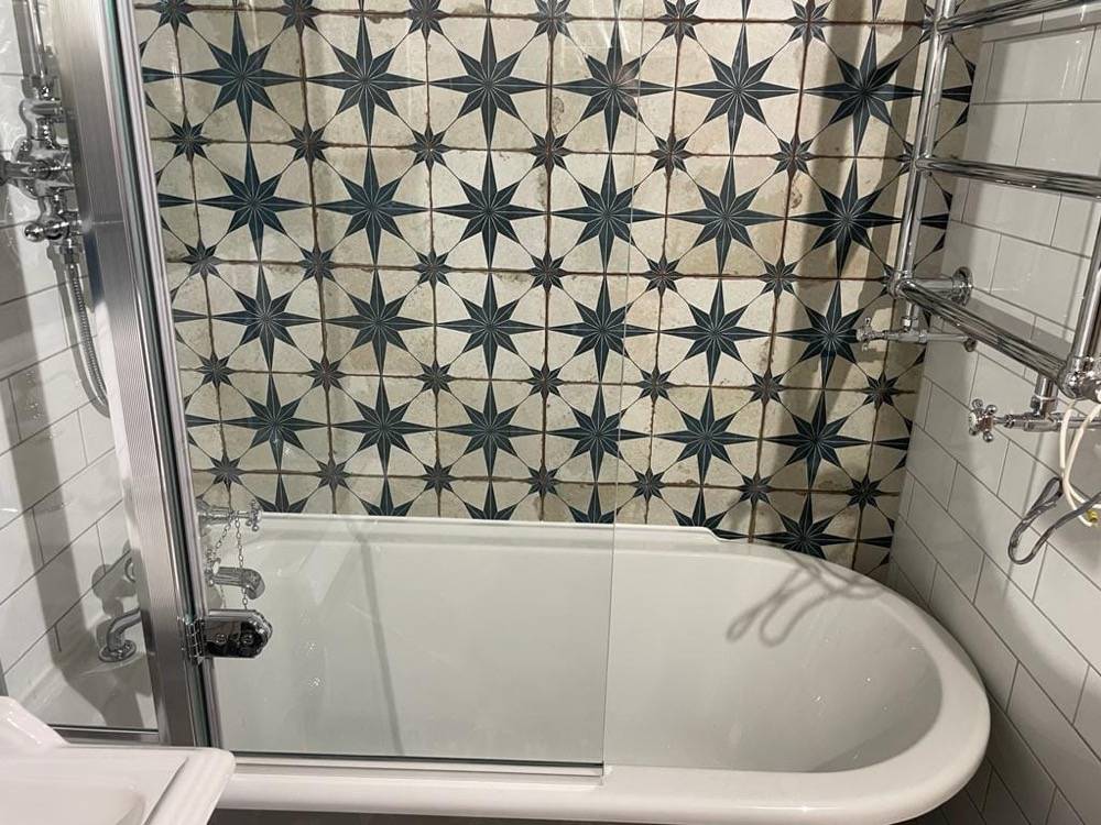Bathroom with starry feature tile wall and shower-over-bath by DR Construction