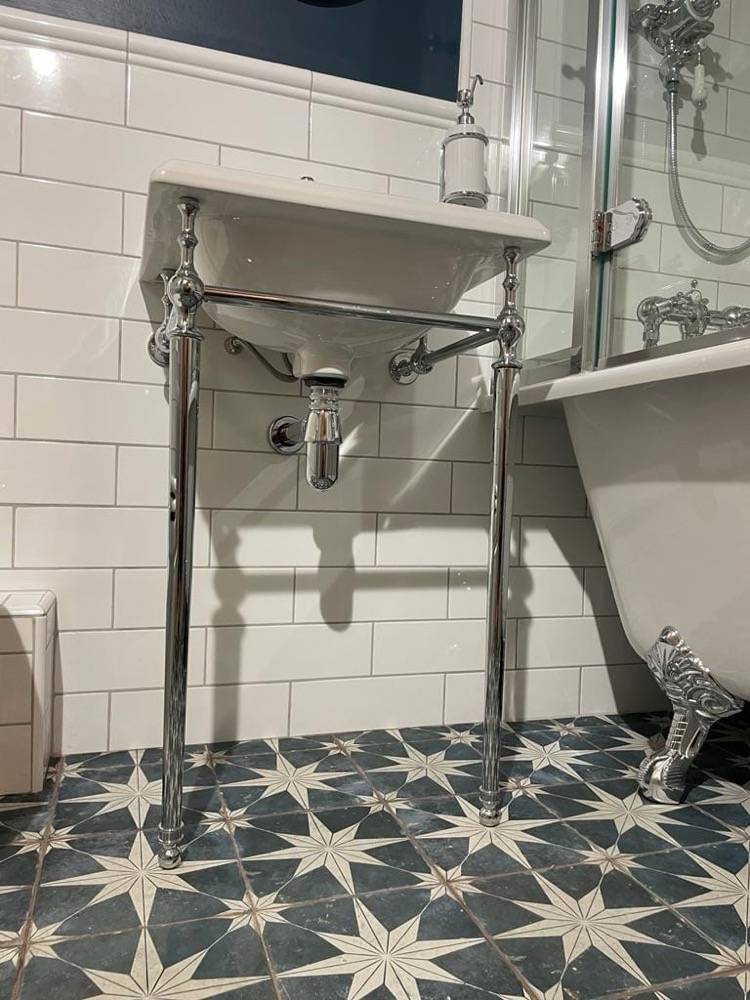 Traditional pedestal sink on patterned starry tile floor in refurbished bathroom