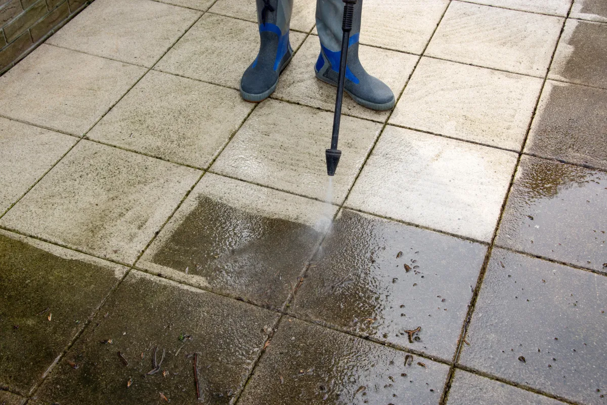 man jet washing a patio