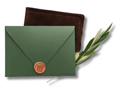 a photo of a eucalyptus branch tucked beneath a green envelope that's sealed with a copper-colored wax seal.