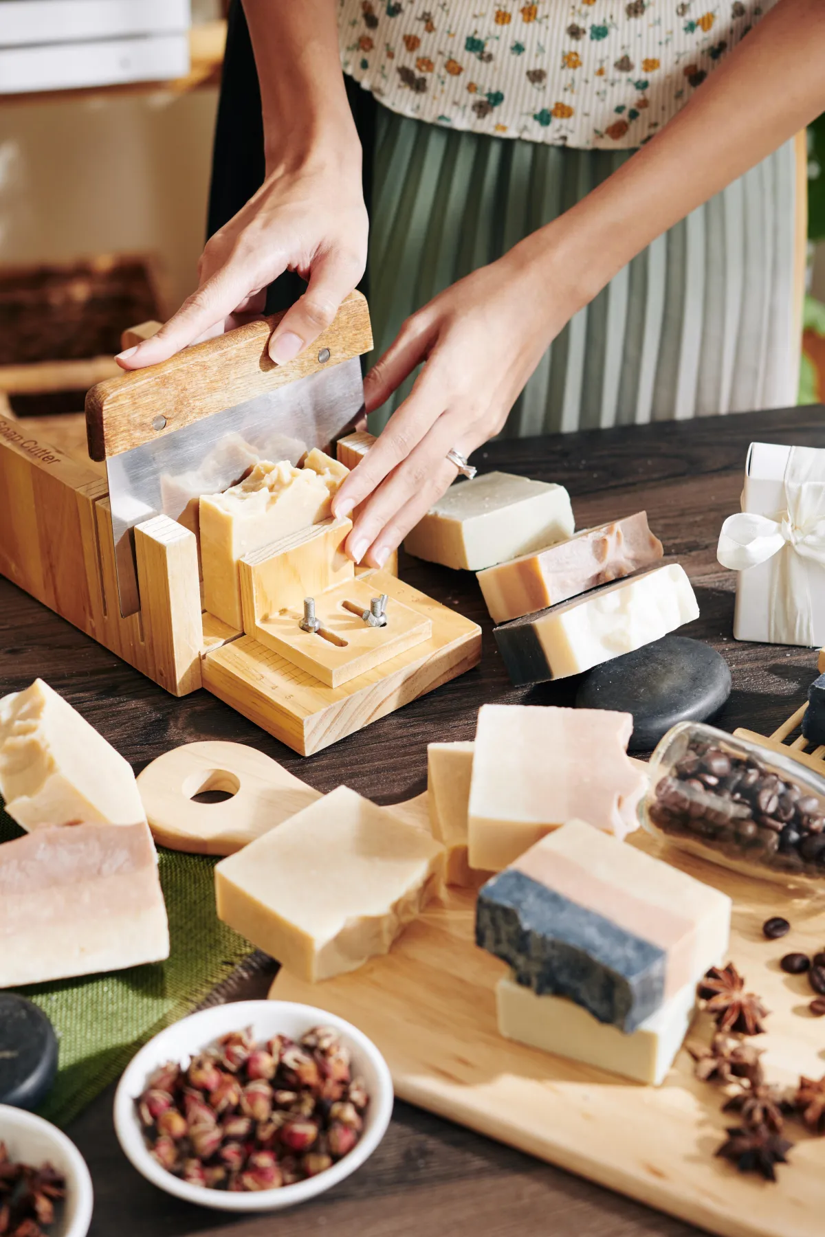 Hands gently working raw botanical ingredients into soap, focusing on tactile textures
