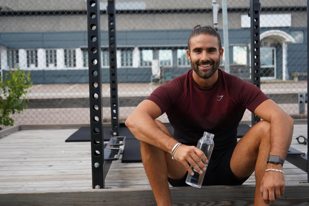 topless man in black pants holding black and yellow exercise equipment