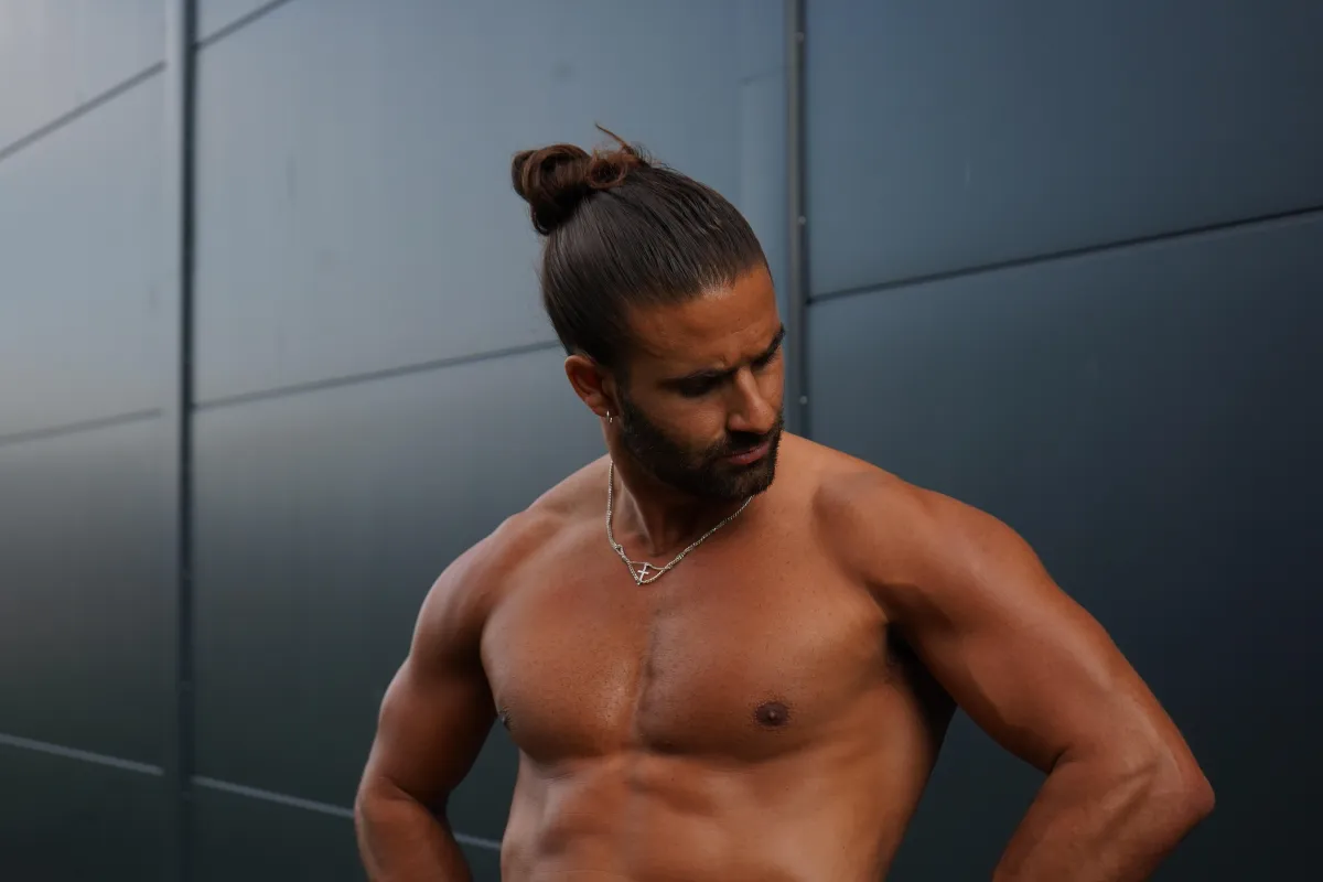 topless man in black shorts carrying black dumbbell