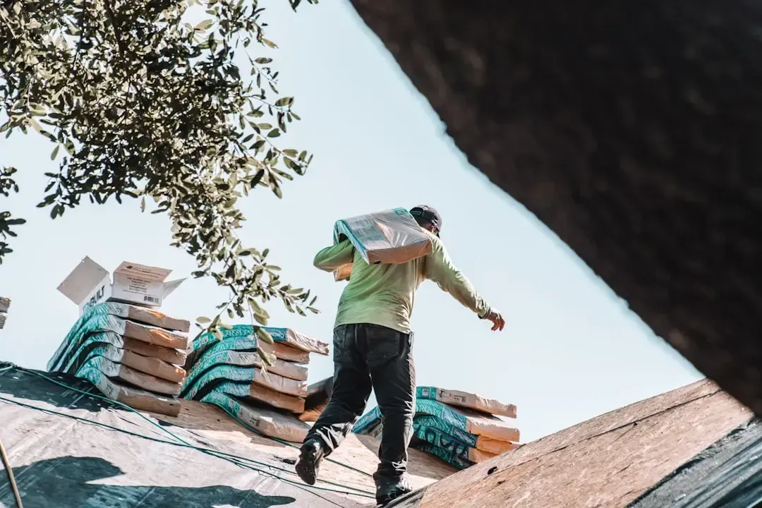 A professional roofer carrying materials across a residential roof during a repair project.