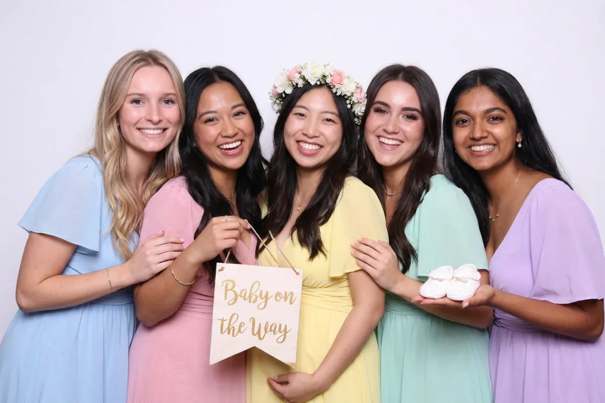 Baby shower photo booth with lush floral white rose backdrop at NYC celebration venue