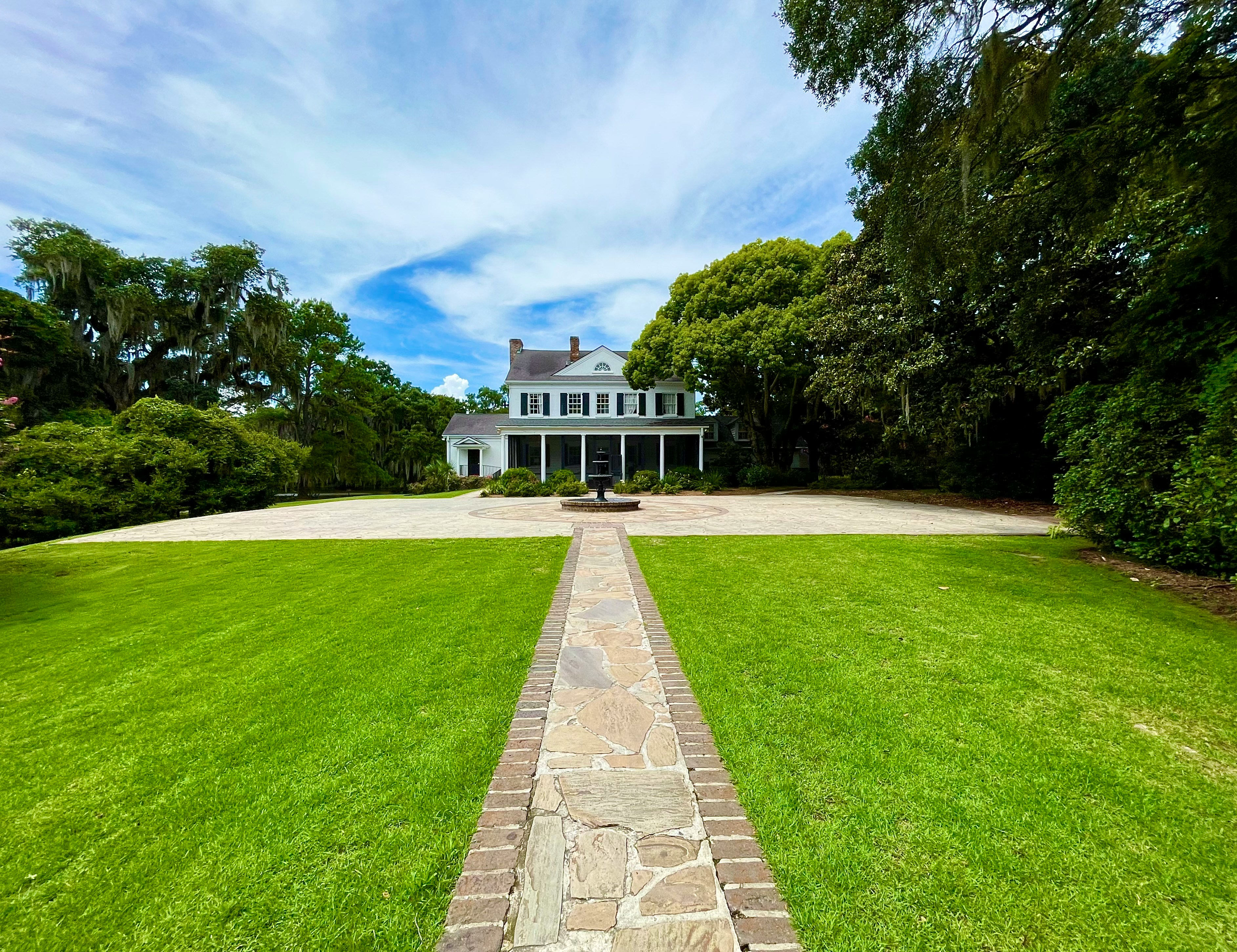 stone pathway leading to big white and terracotta bungalow