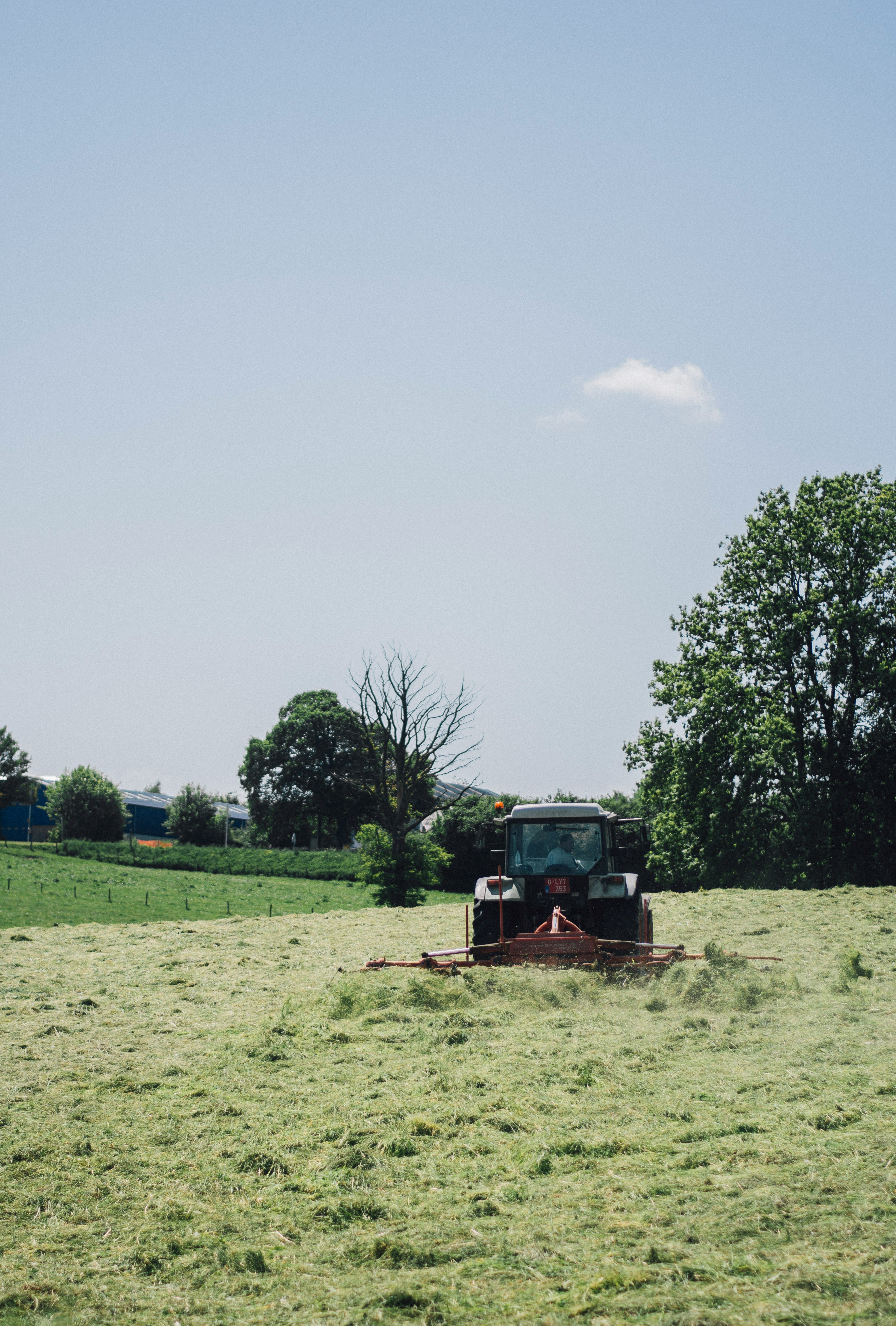 farmer tractor mowing grass on field