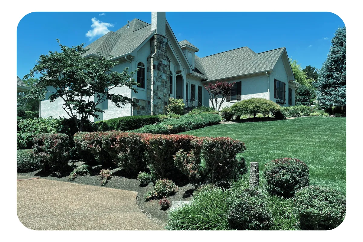 Manicured bushes in front of elaborate white rock home