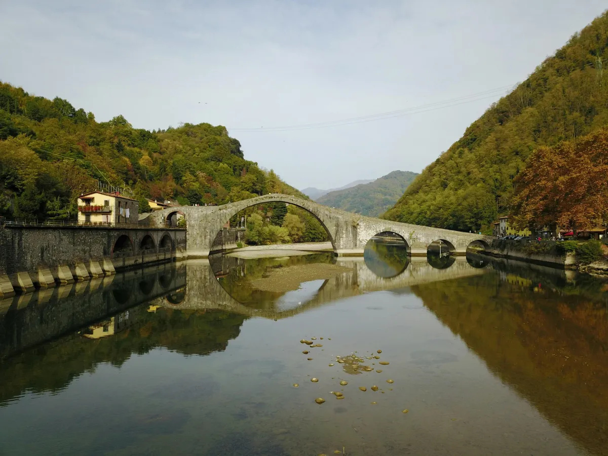 Old Stone Bridge arching over quiet river waters with green hills rising on either side of the bridge