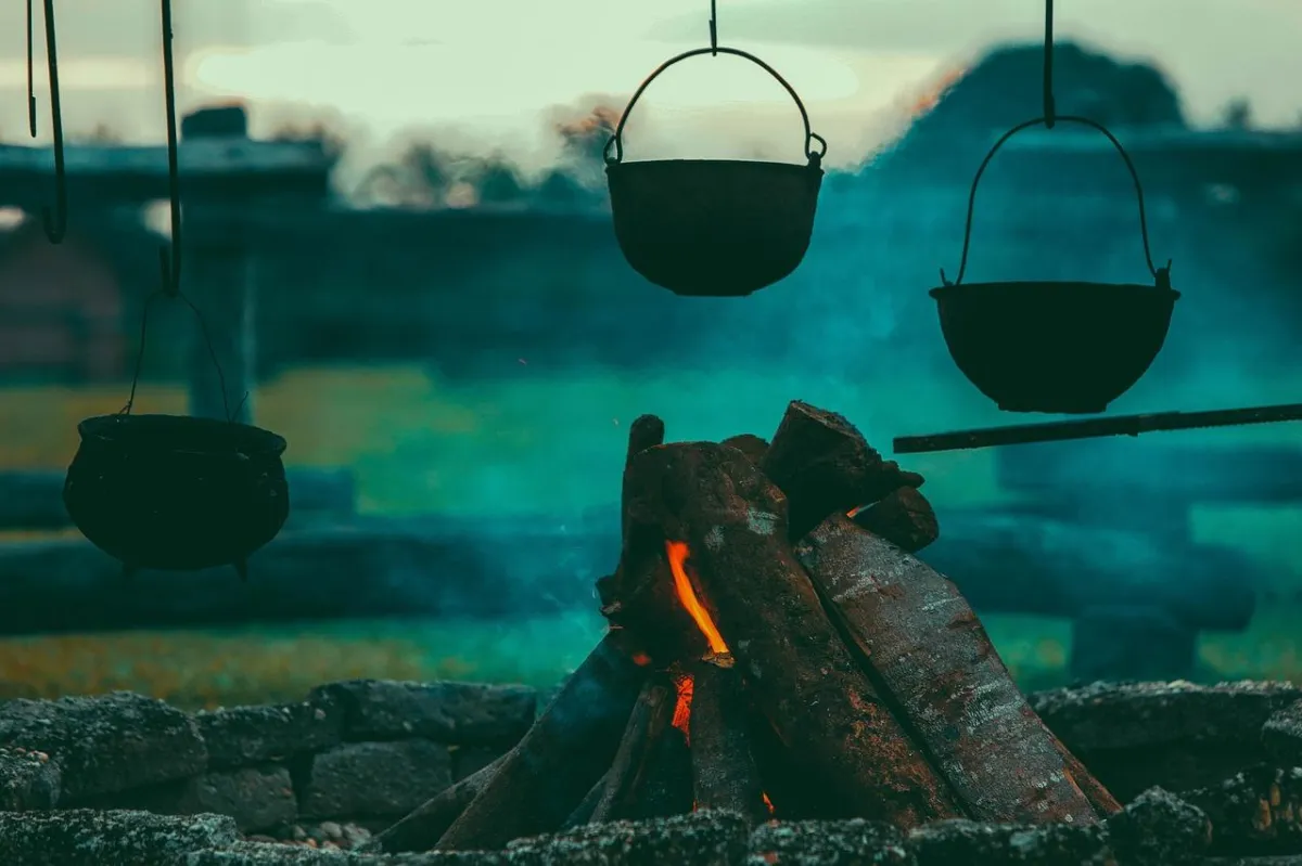 Orfeo's campfire smoking and smoldering with cast iron pots hanging above the gentle flames and smoke