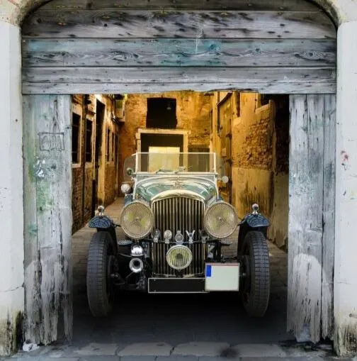 Sir San's Elite Selfer, like a 1920s Model T, sitting in the open doorway of a barn