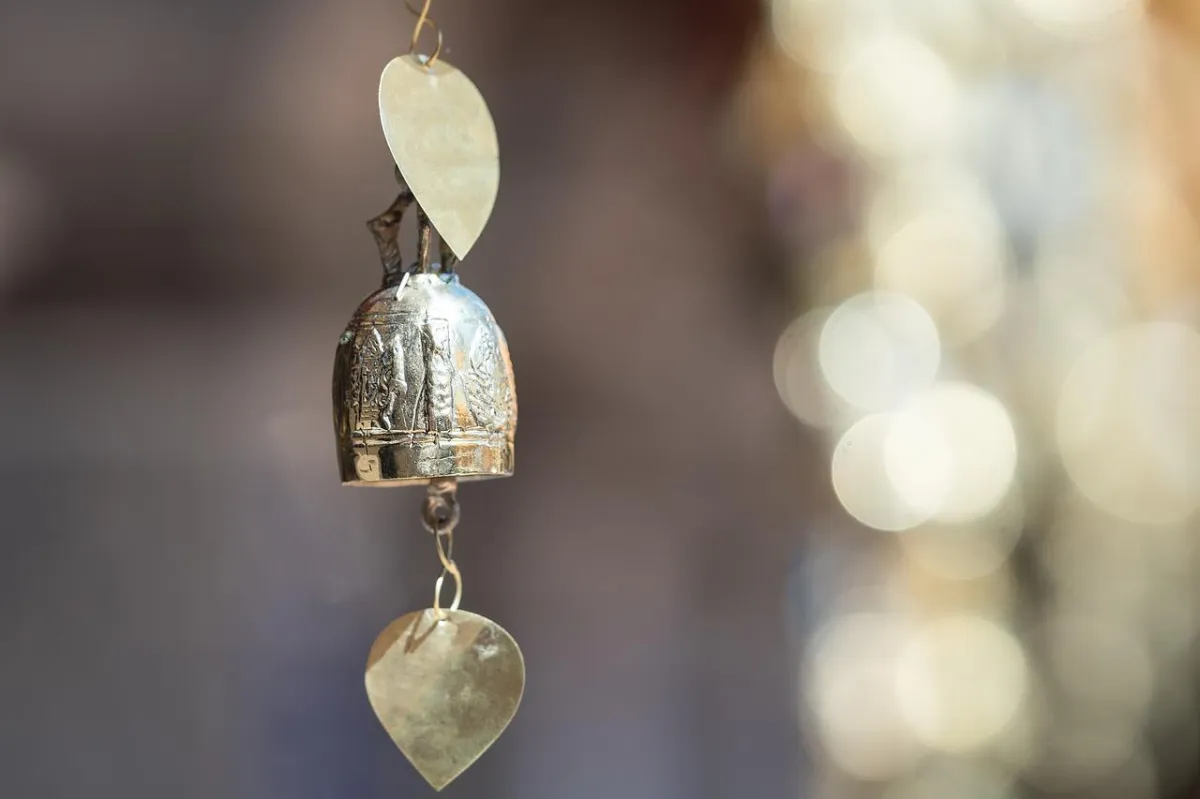 Close-up of Elke's bell, a small dangling, ornate, gold bell hanging suspended