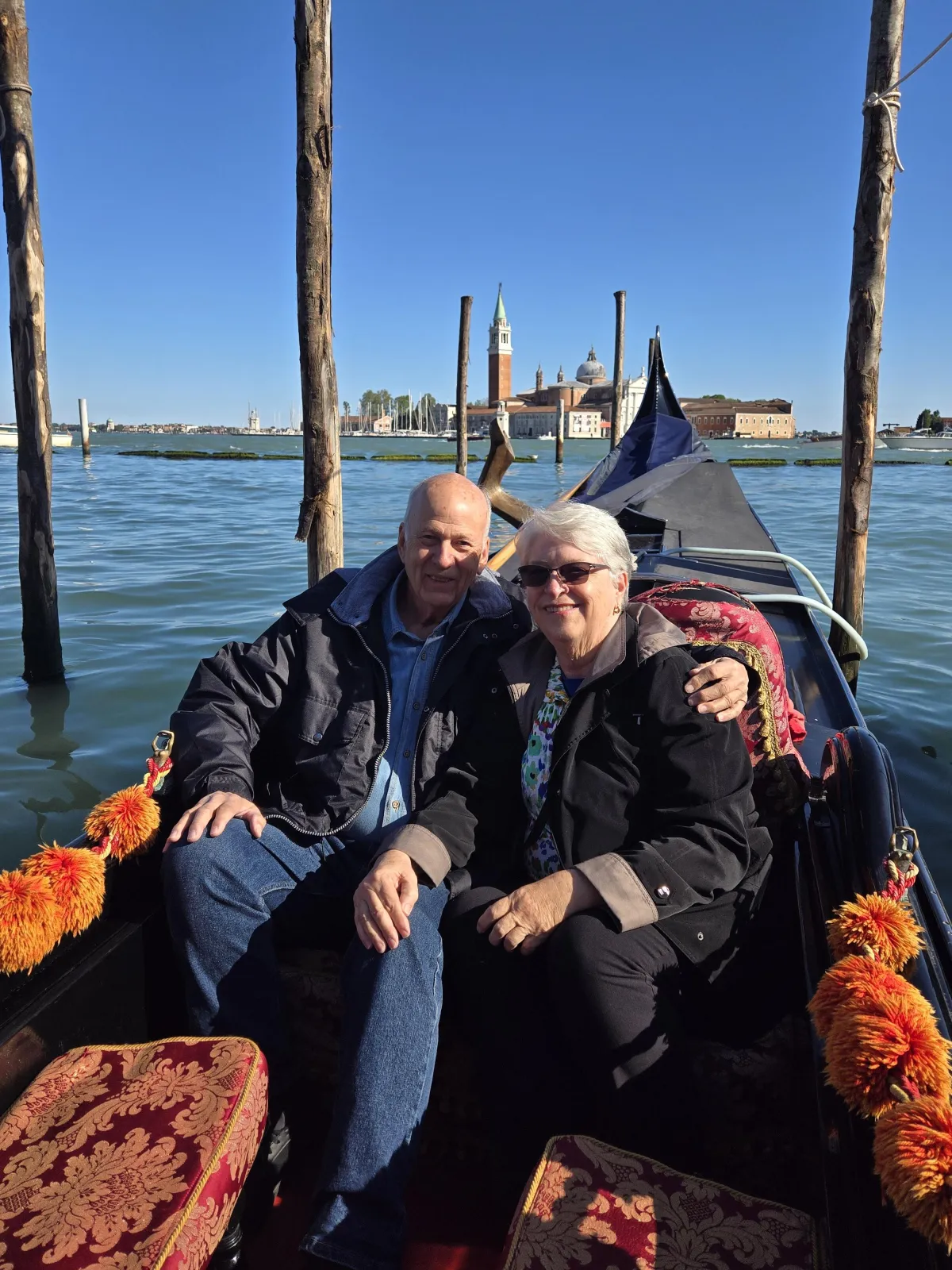 C. S. Fitzpatrick sitting in a gondola in Venice in the arms of her husband as they ride on blue waters underneath an even bluer sky