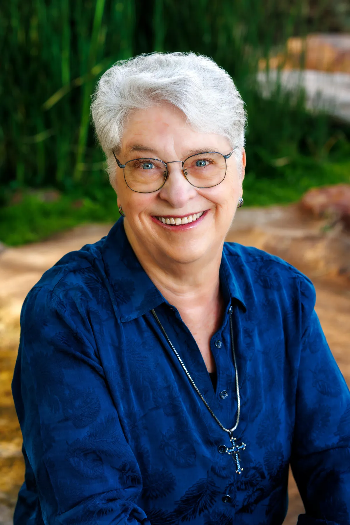Photo of author C. S. Fitzpatrick seated and smiling in a vibrant blue shirt, wearing a warm smile and wire-frame glasses