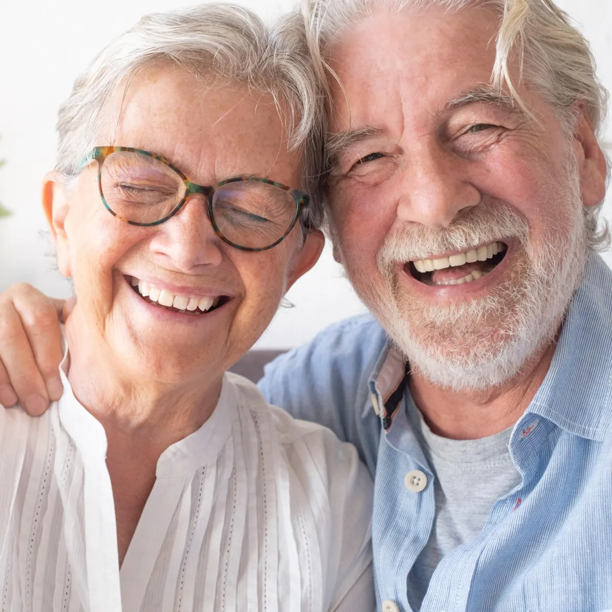 Older man and woman sitting next to each other laughing and smiling