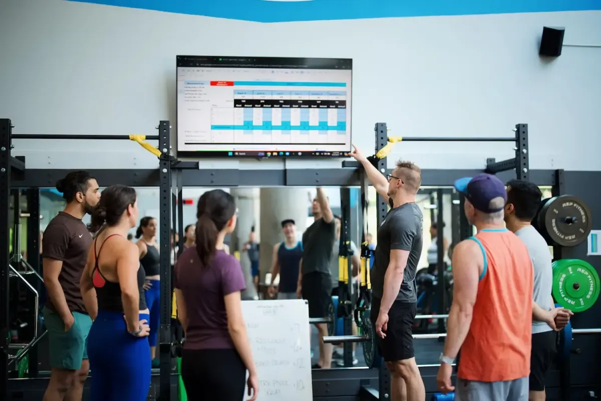 A small group of training members looking at screen, which a coach is pointing to. 