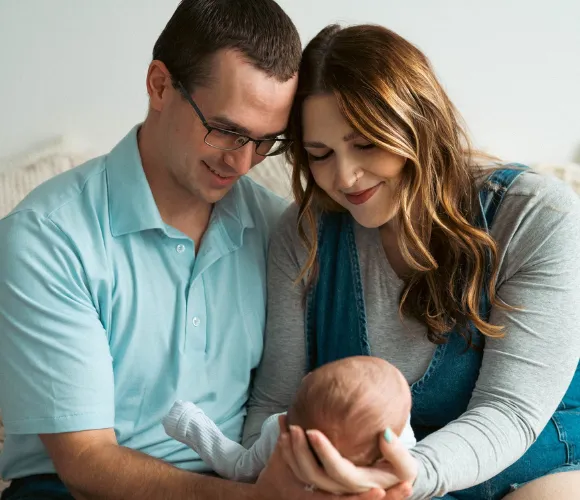 Parents cradling a newborn in their hands