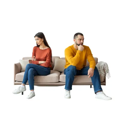 Photo of a couple sitting apart on a couch, looking distant and upset — symbolizing relationship overwhelm