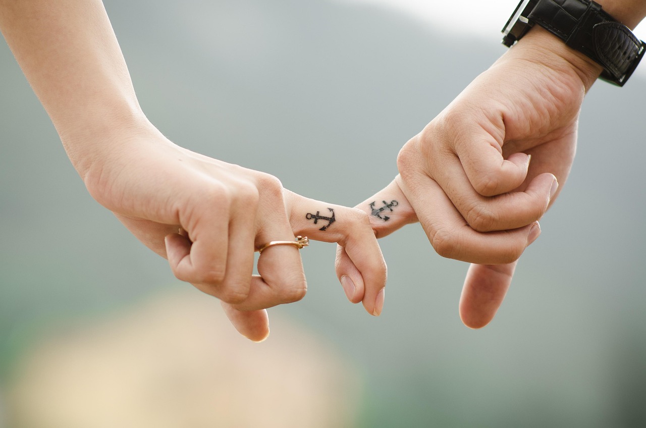 Hands with fingers linked with tattoos on fingers