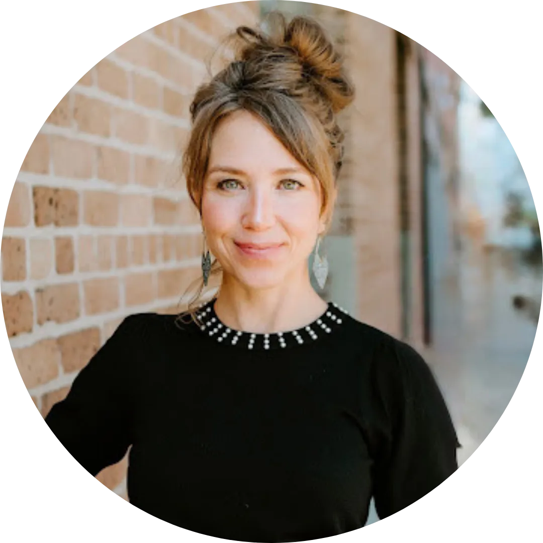 Meg Lamm, Licensed Massage Therapist and business mentor, smiling confidently against a brick wall background