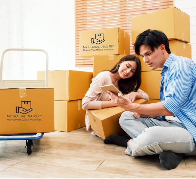 Couple reviewing their international moving quote on a tablet beside My Global Delivery boxes