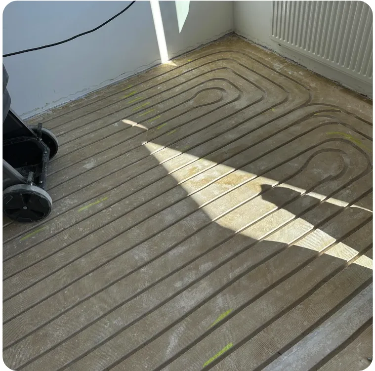 Zonlicht op nieuw gefreesde vloerverwarmingssleuven tijdens renovatie
