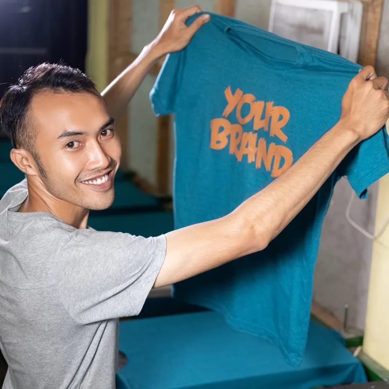 Man holding custom-printed t-shirt showcasing brand apparel printing services.