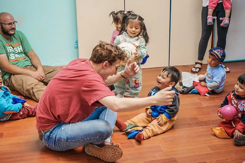 A volunteer smiling and playing with a young child during an orphanage volunteer trip