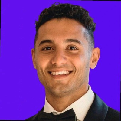 Professional headshot of a smiling man in a tuxedo against a purple background, representing the team at Arin Russell Buyers Agents, emphasizing trust and expertise in property advocacy.