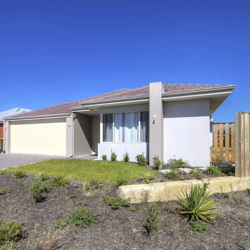 Modern single-story house with a landscaped front yard, showcasing a garage and large windows under a clear blue sky, representing successful property purchases by Arin Russell Buyers Agents.