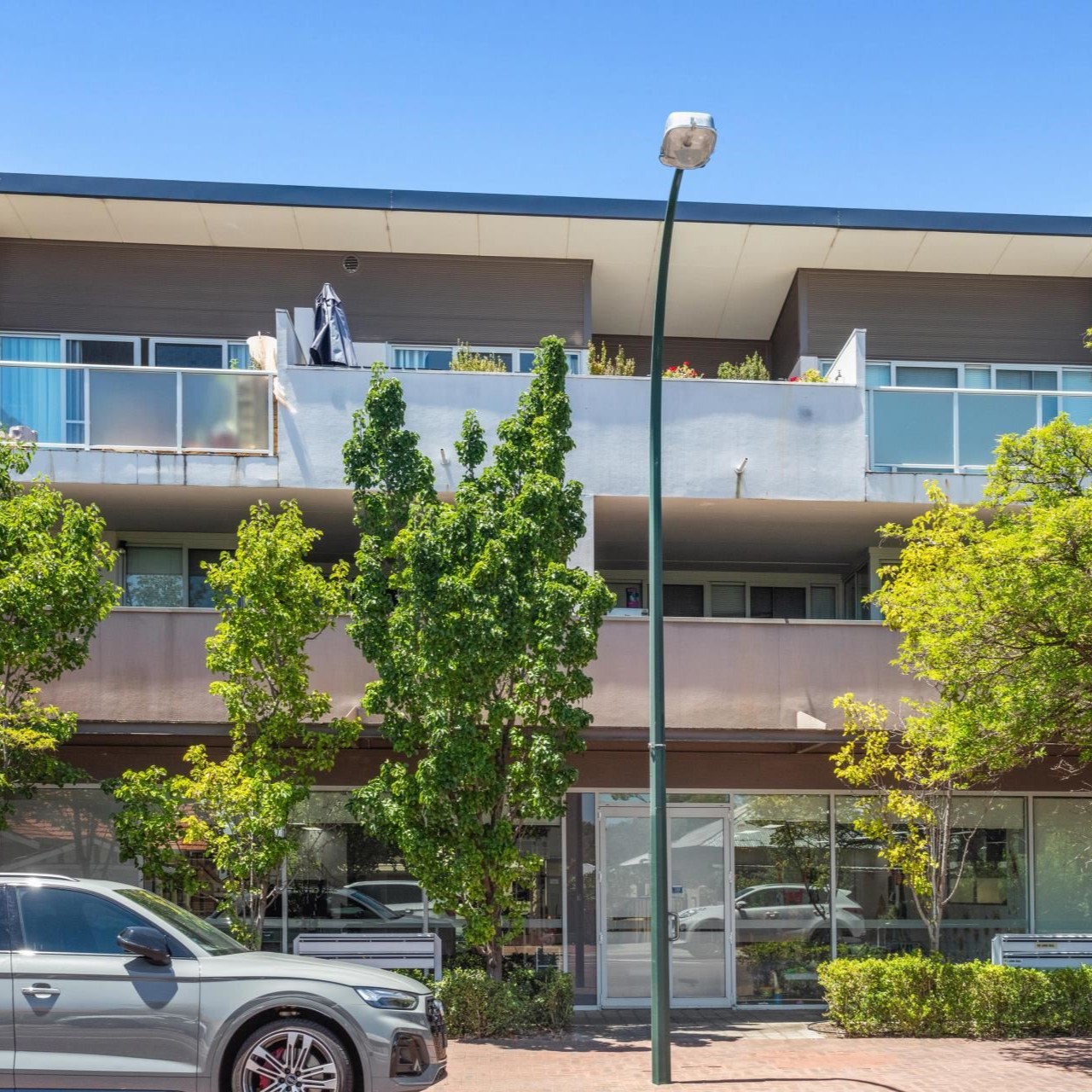 Modern apartment building with greenery, showcasing a safe and appealing living environment, relevant to family home search by Arin Russell Buyers Agents.