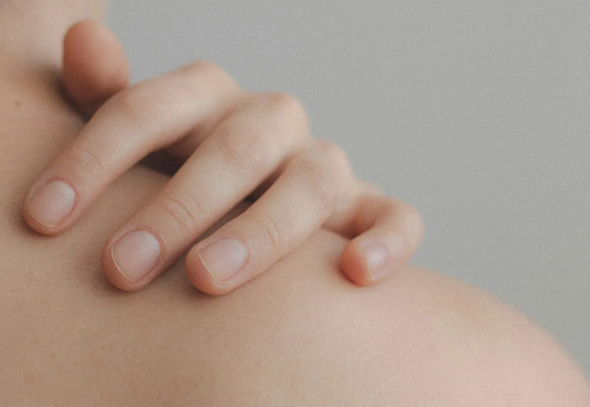 A hand holding a shoulder - bare skin