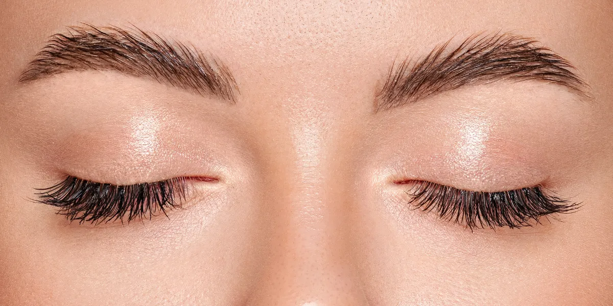 Close up of a young woman's eyes closed with lash and brow definition.