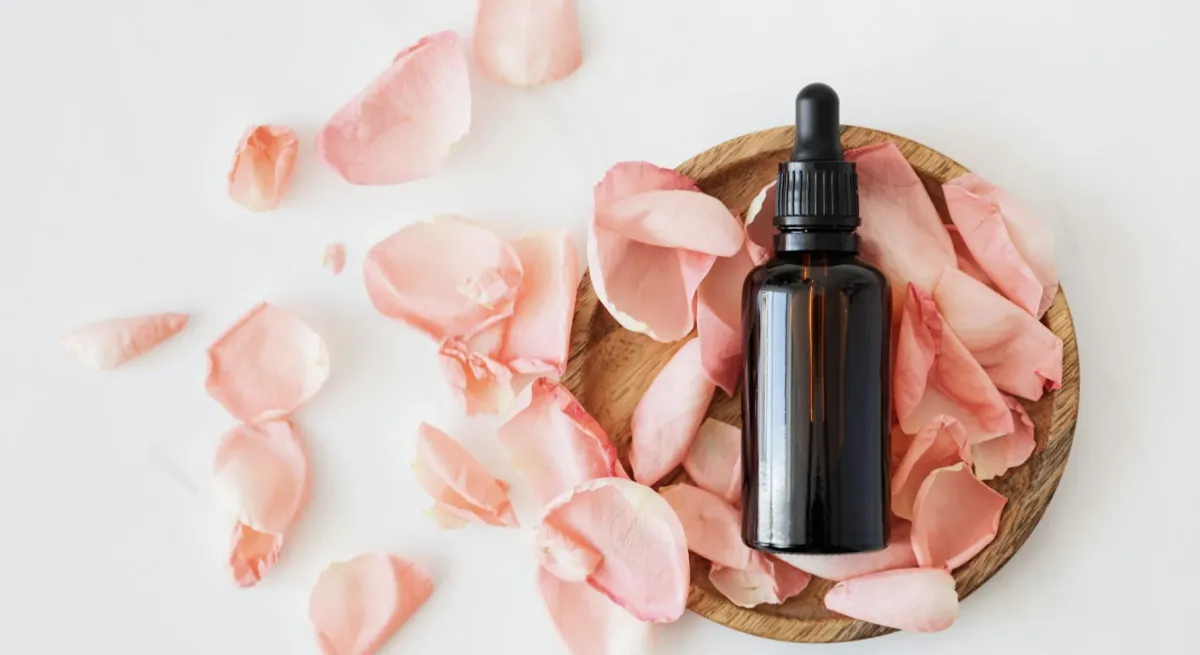 Essential oil bottle placed on top of rose petals 