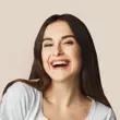 a woman with long hair smiling and wearing a white shirt