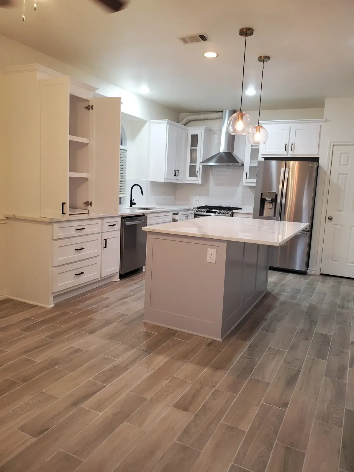 a kitchen with a wood floor and white cabinets