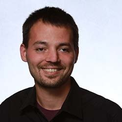 Portrait of a Black female cybersecurity consultant in her 30s, smiling confidently, with a blurred server room background. 1:1 aspect ratio.