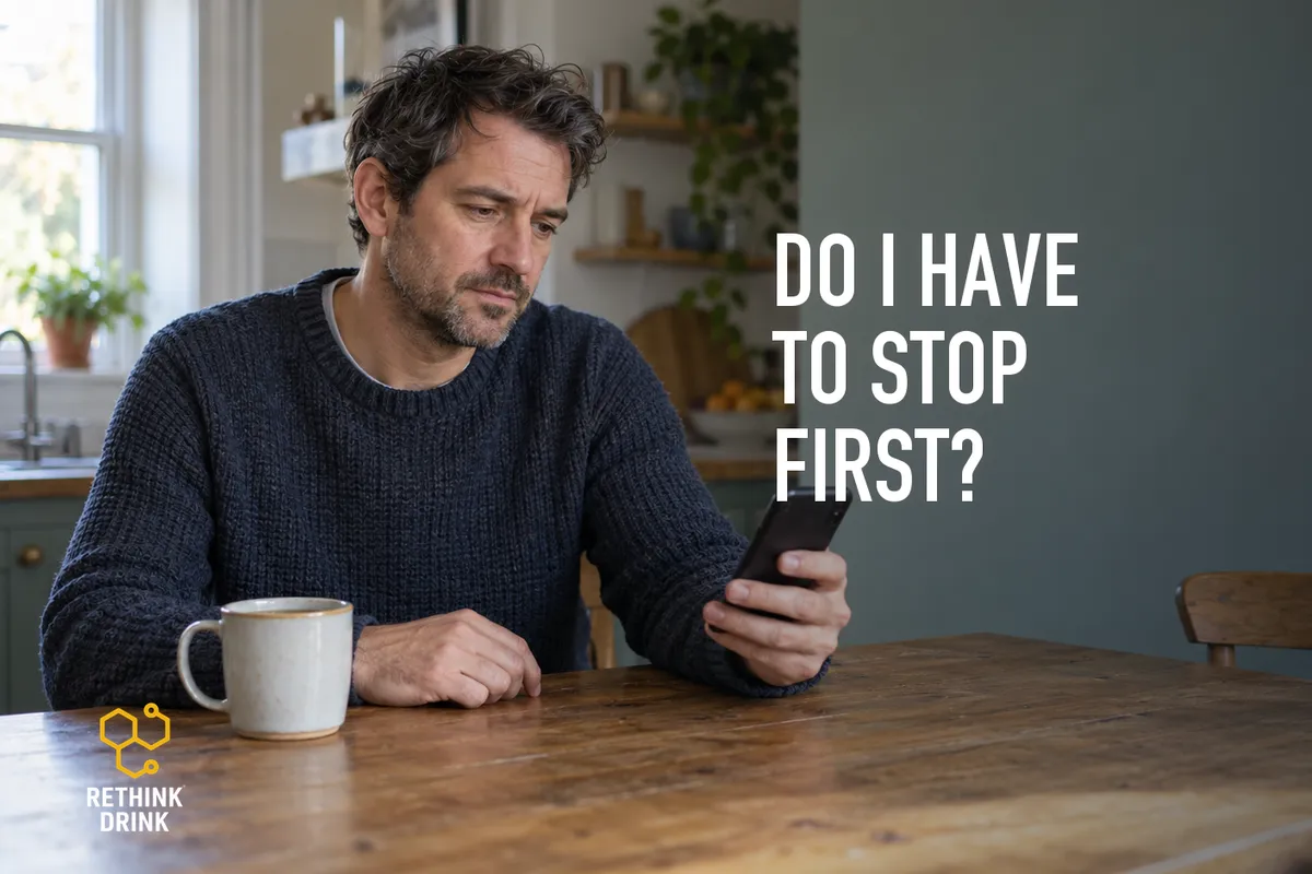 A man at his kitchen table with his phone, wondering whether he has to stop drinking first