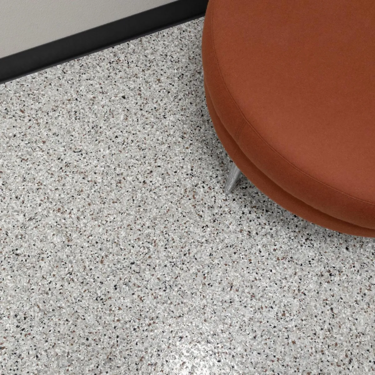 Round stool on speckled full chip garage floor, showcasing seamless and clean finish for indoor spaces