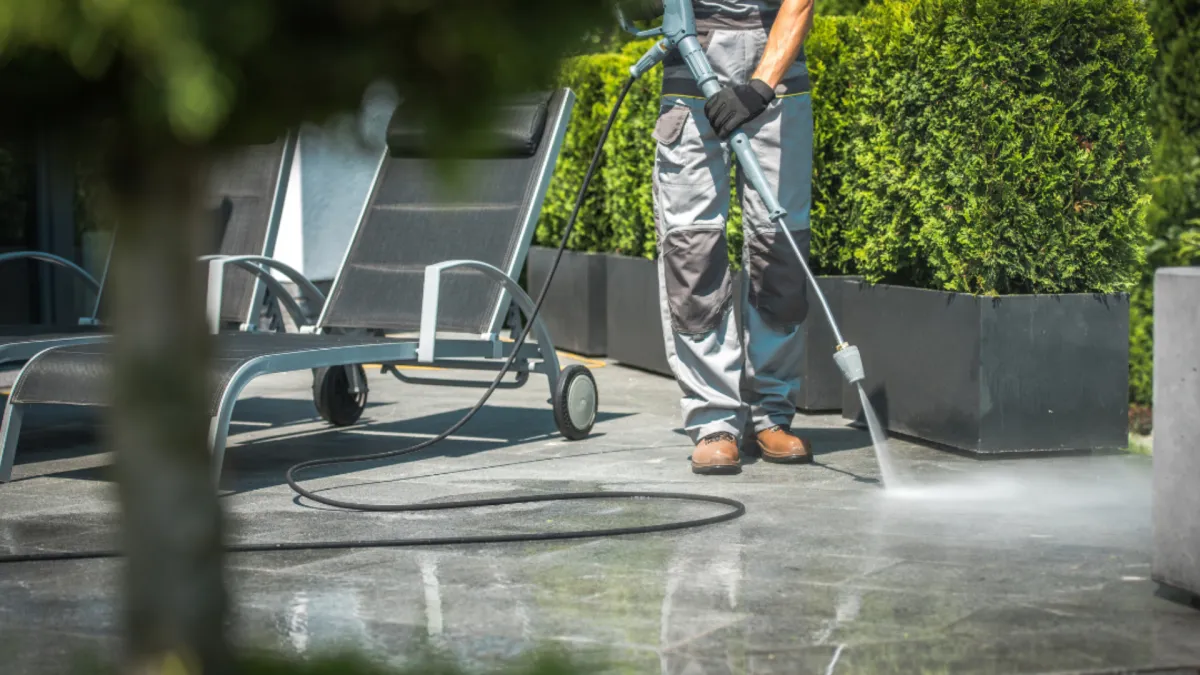 Man outside water blasting concrete 