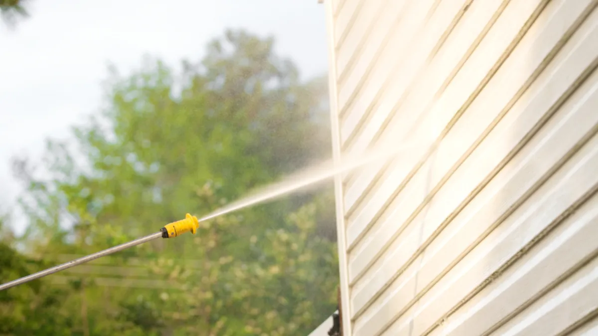 Water blaster soft washing exterior of house 