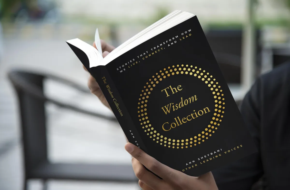 Person holding The Wisdom Collection book, an international best-selling leadership anthology featuring Kristen Arnold’s chapter on why great leaders replace themselves.