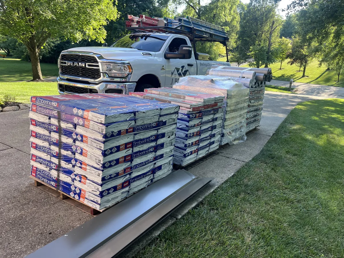 Jbucks Gutters branded truck next to a stack of roofing shngles