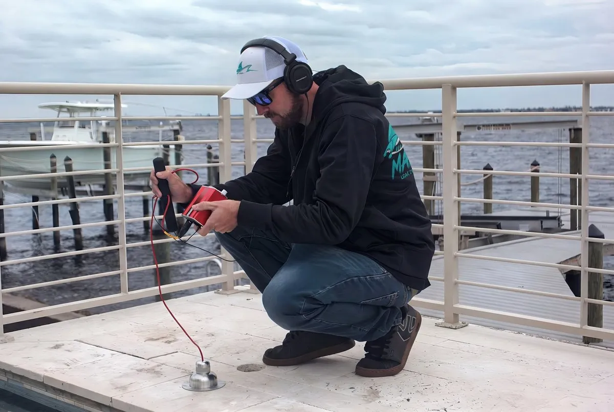 Manta Leak Detection technician setting up electronic leak detection equipment on a pool deck in Cape Coral