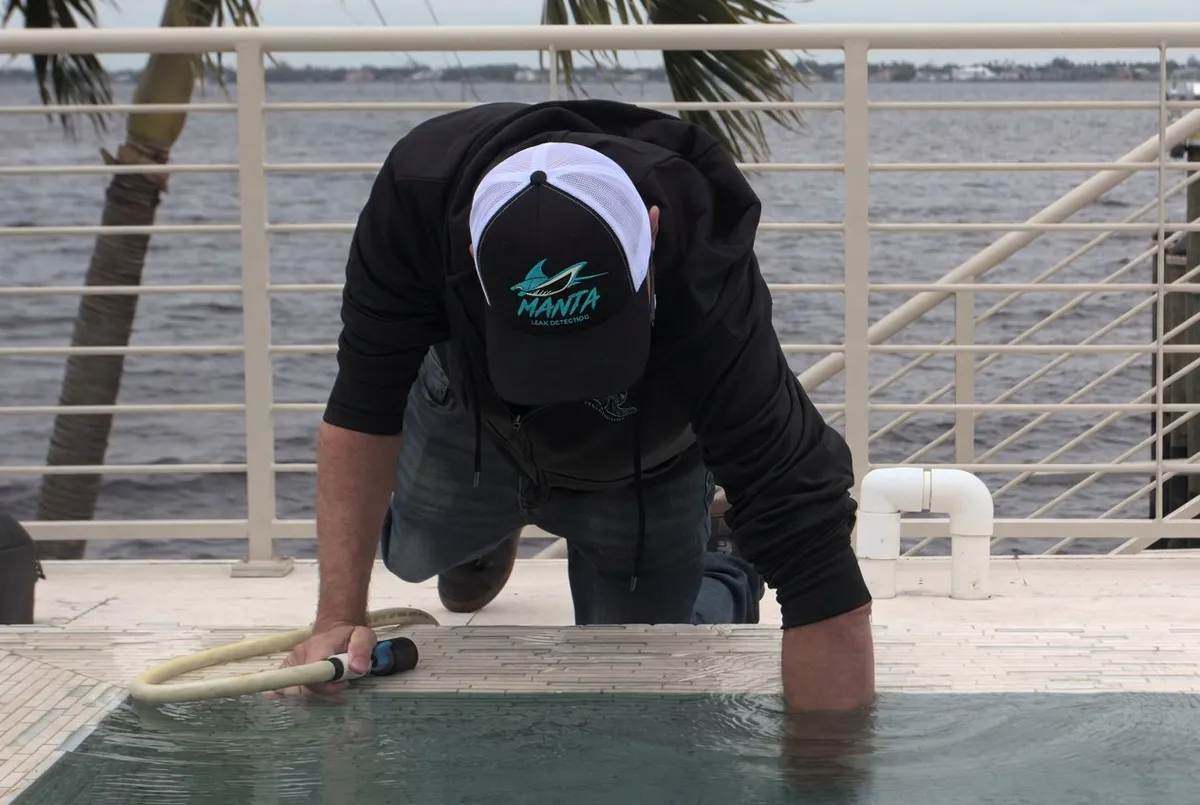 Manta Leak Detection technician kneeling at the pool edge performing a leak inspection in Cape Coral