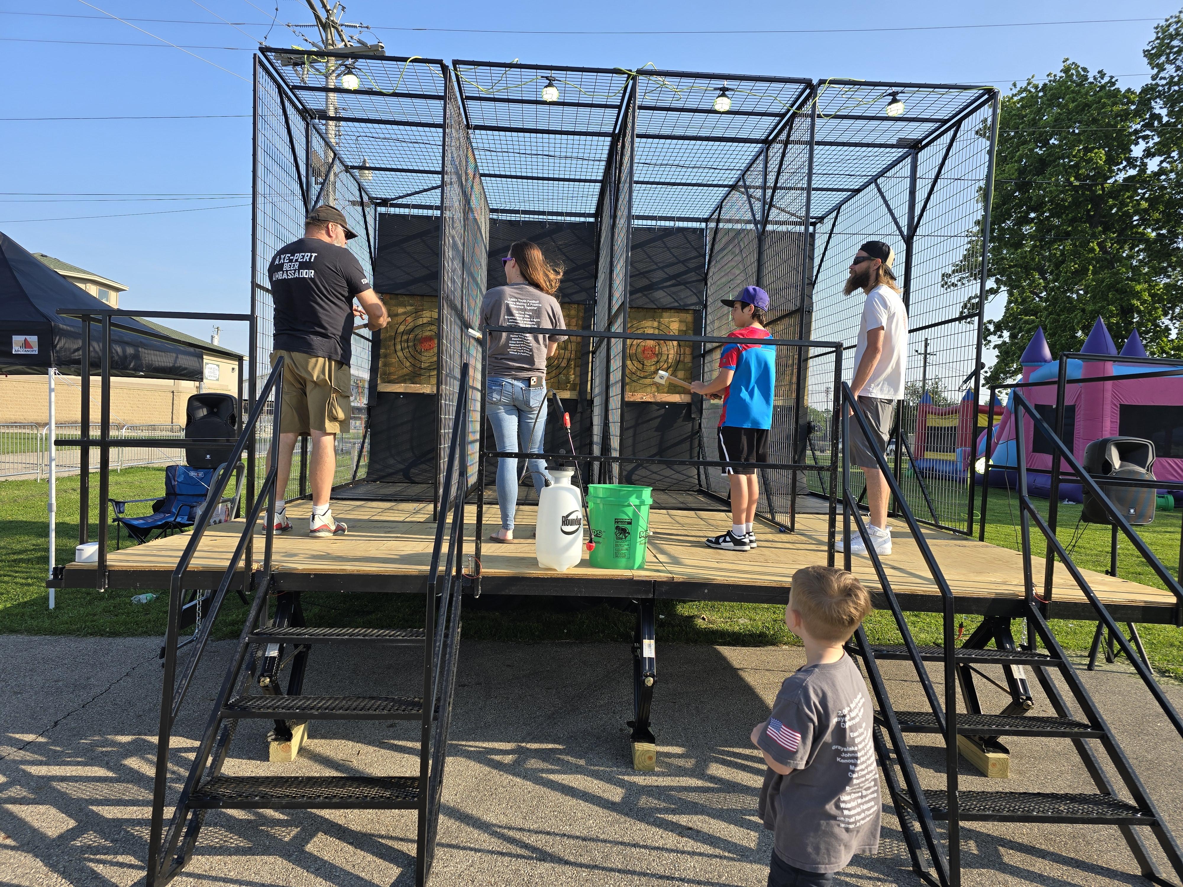 Guests throwing axes at Hold My Beer’s mobile axe throwing unit during a Kenosha community event